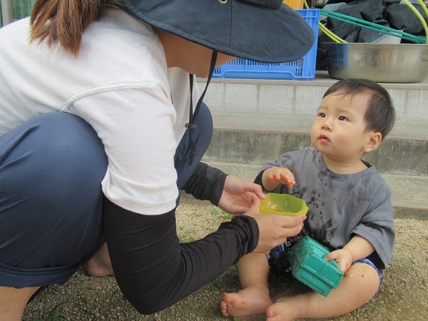 保育者と一緒に水遊びをしている