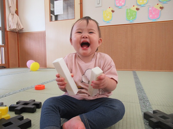 ブロックを太鼓のばちのようにして遊ぶ女の子