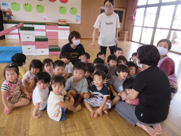 地震の放送を聞いて保育者の元へ集まる子どもたち