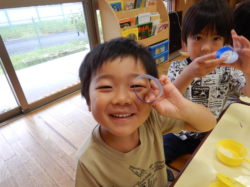 丸めた折り紙を見せる男の子