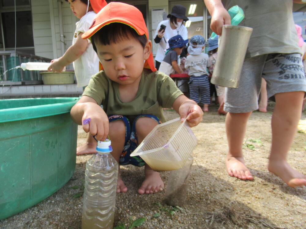 ペットボトルに水を入れている男の子