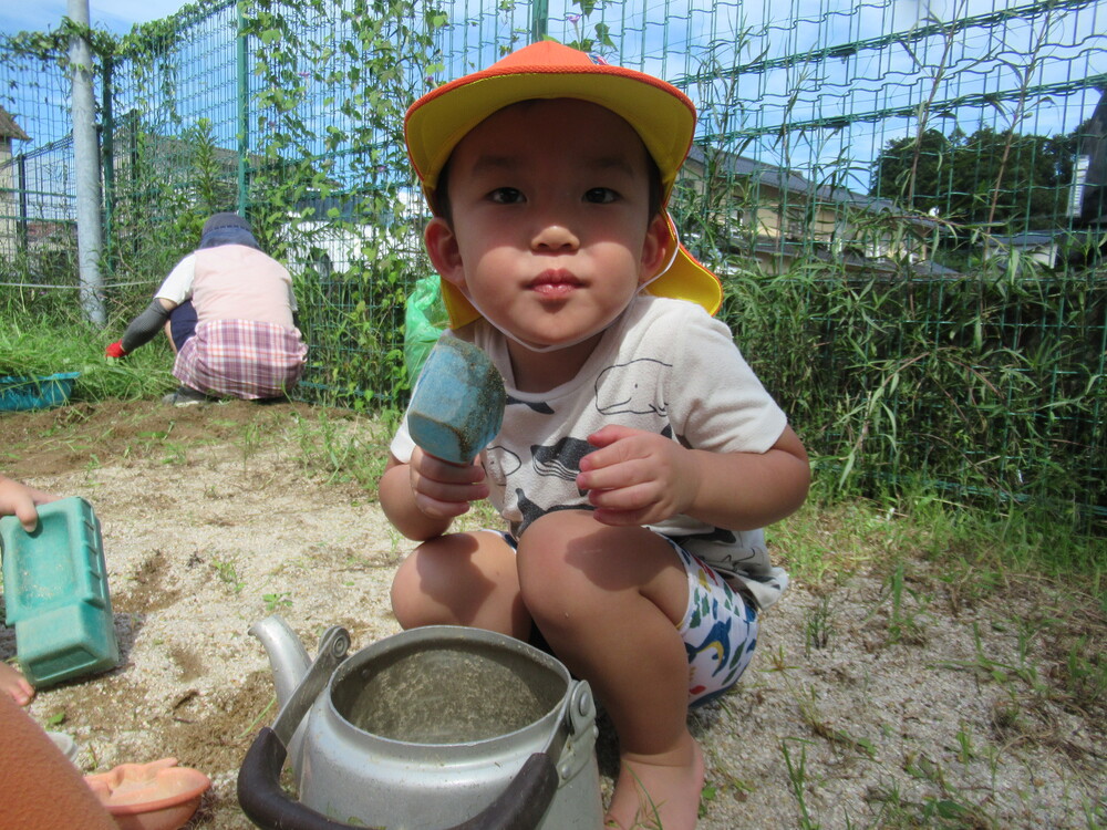 やかんに砂を入れている男の子