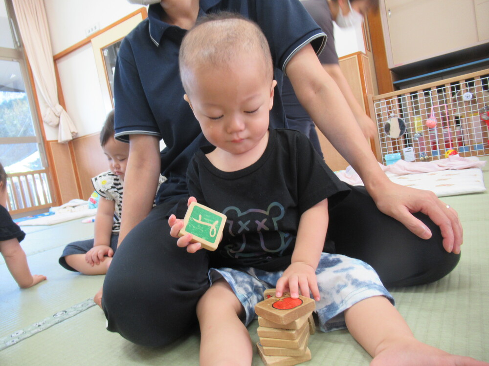 保育者と一緒に積み木を積み重ねて遊ぶ男の子