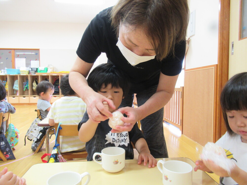 保育者とおにぎり握る男の子