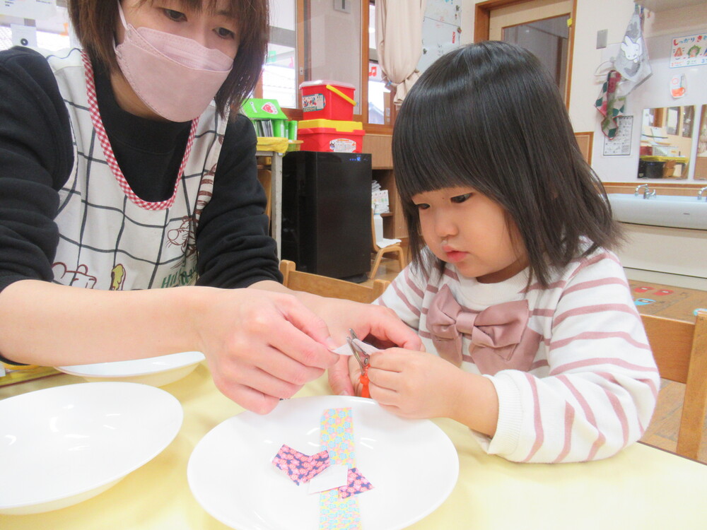 保育者とはさみを使っている女の子