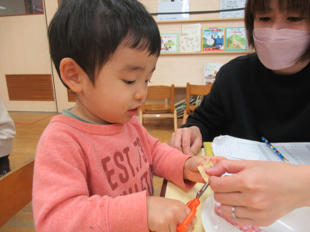 はさみを使って千代紙を切っている男の子