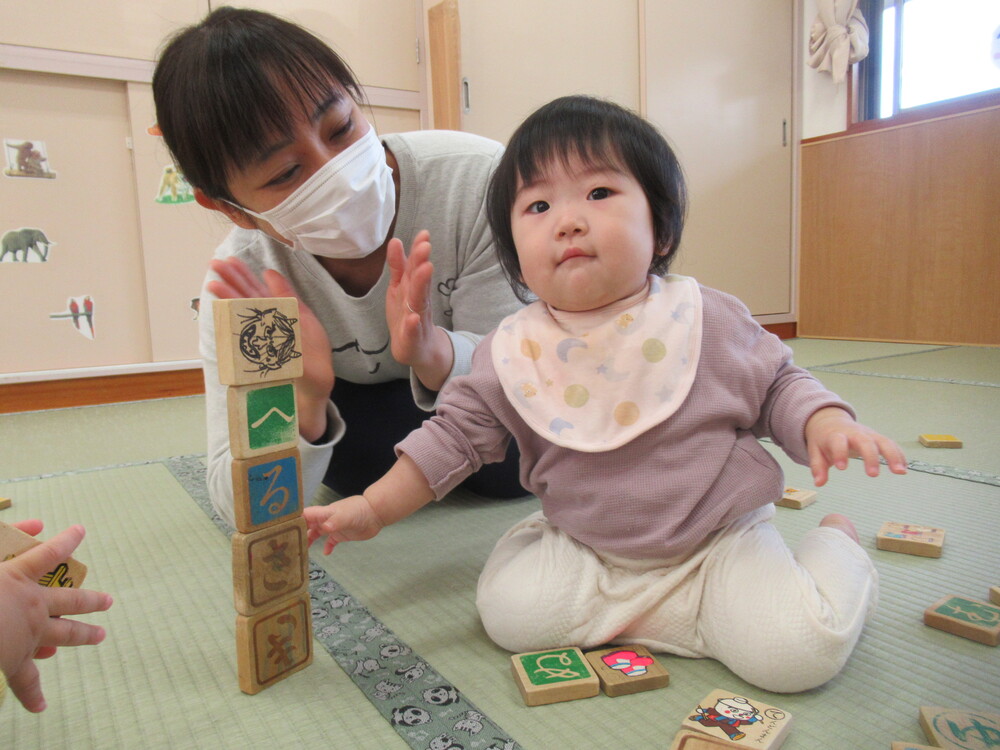 積み木を重ねて嬉しそうな顔をする子ども