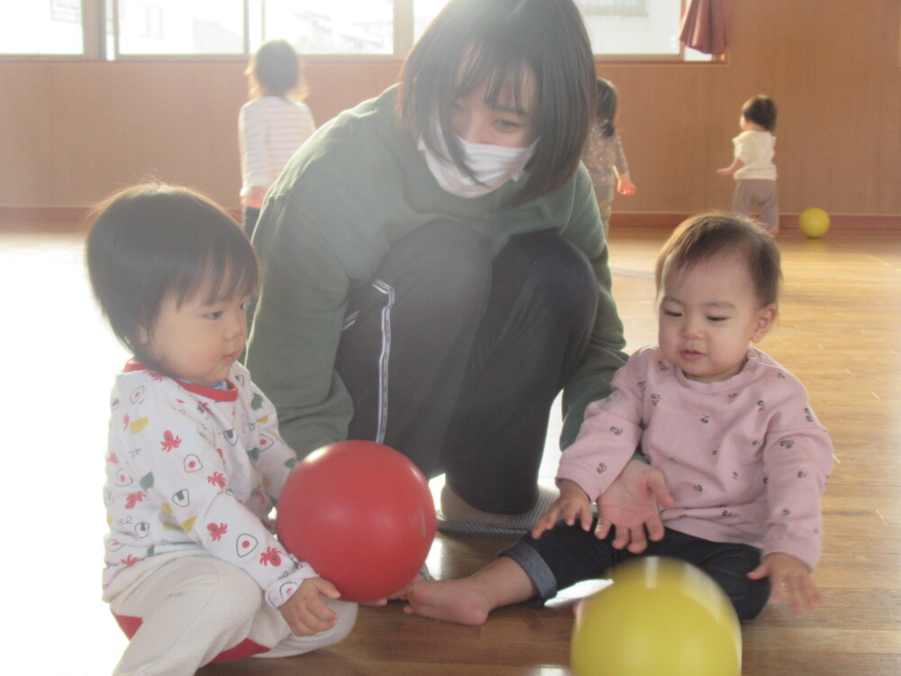 子どもたちが保育者とボールで遊んでいる