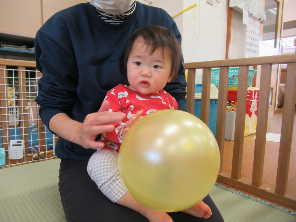 保育者と一緒に風船に触れる子ども