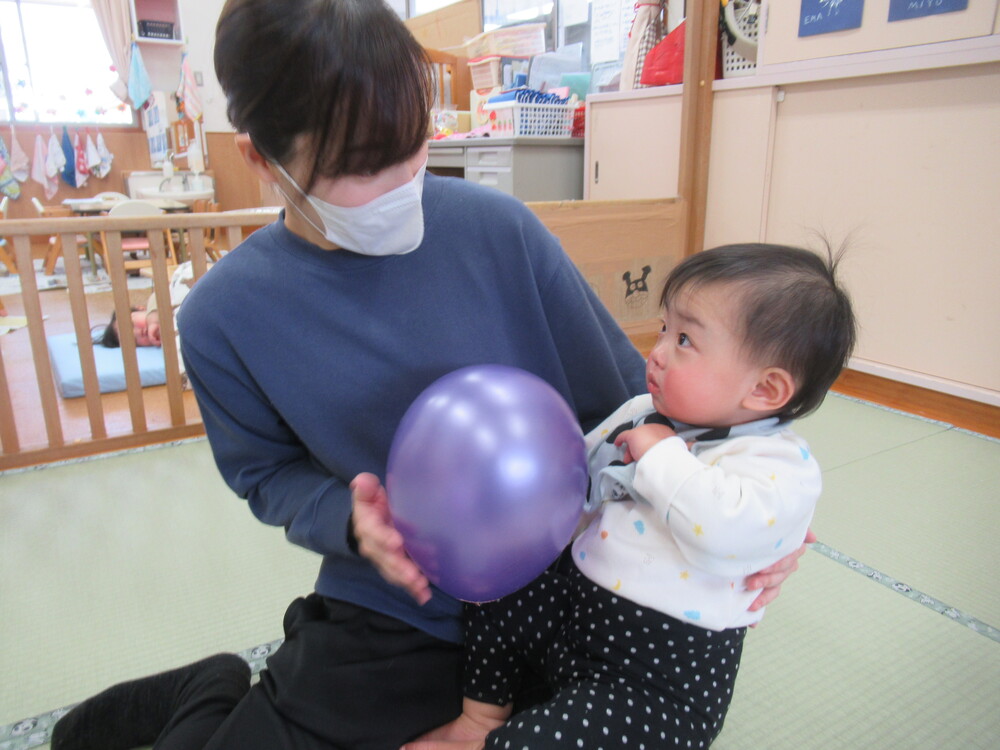 風船に保育者と一緒に触ってみる子ども
