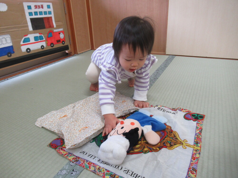 女の子が人形を寝かせている