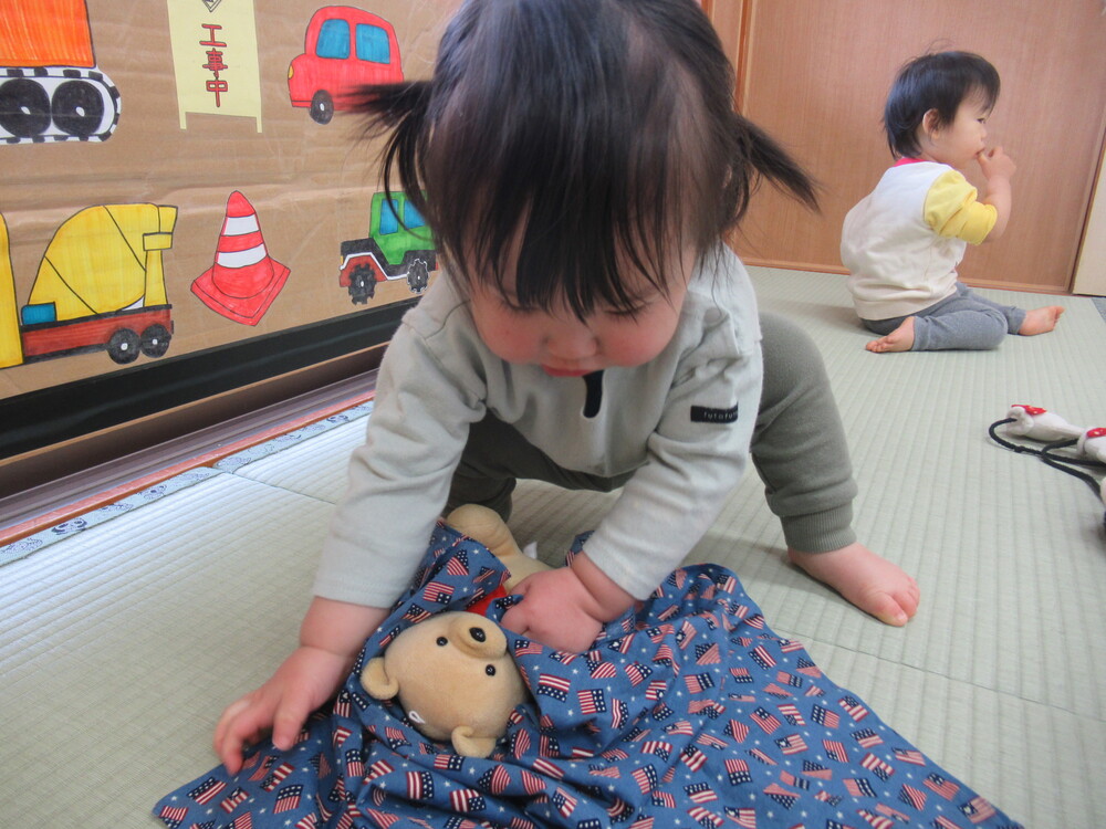 男の子が人形を寝かしつけている