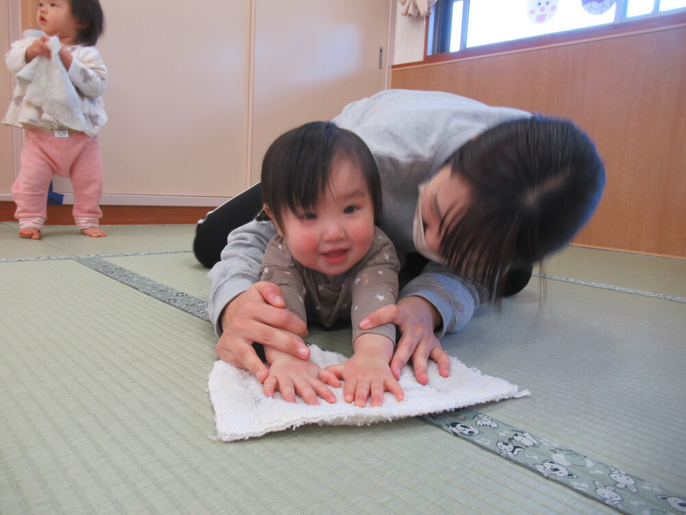 保育者と一緒に雑巾がけをする子ども