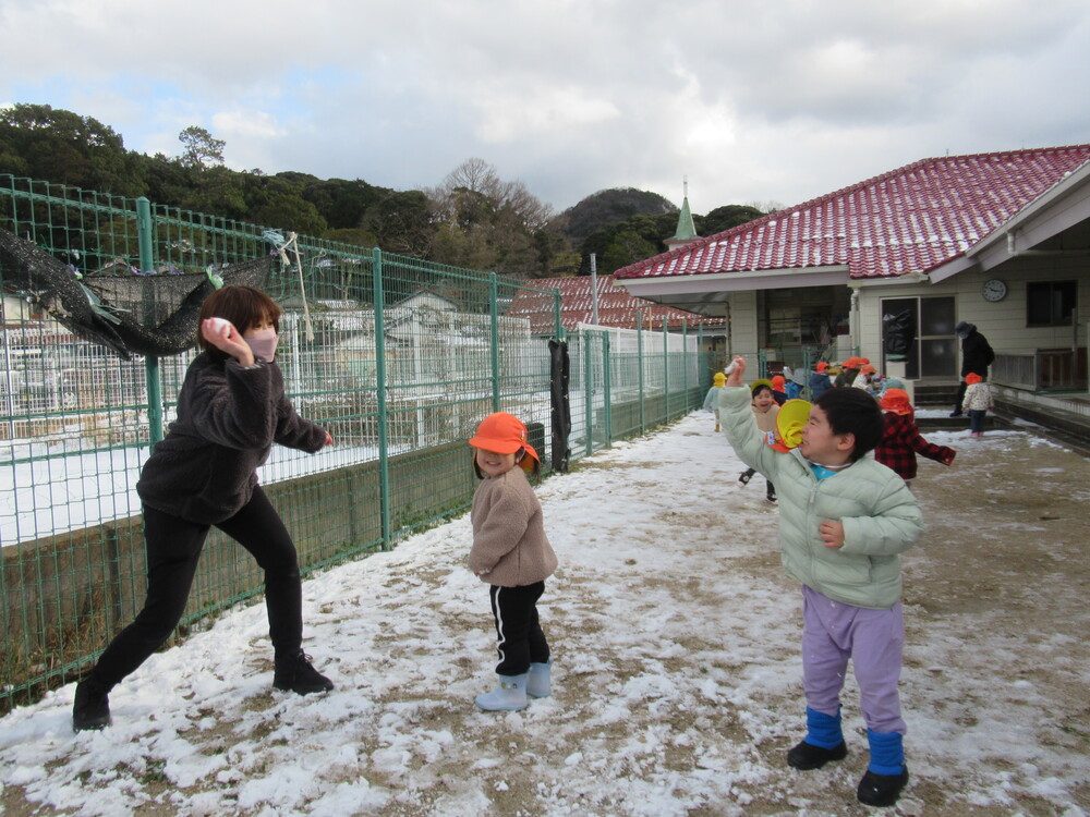 保育者と雪合戦をする子どもたち