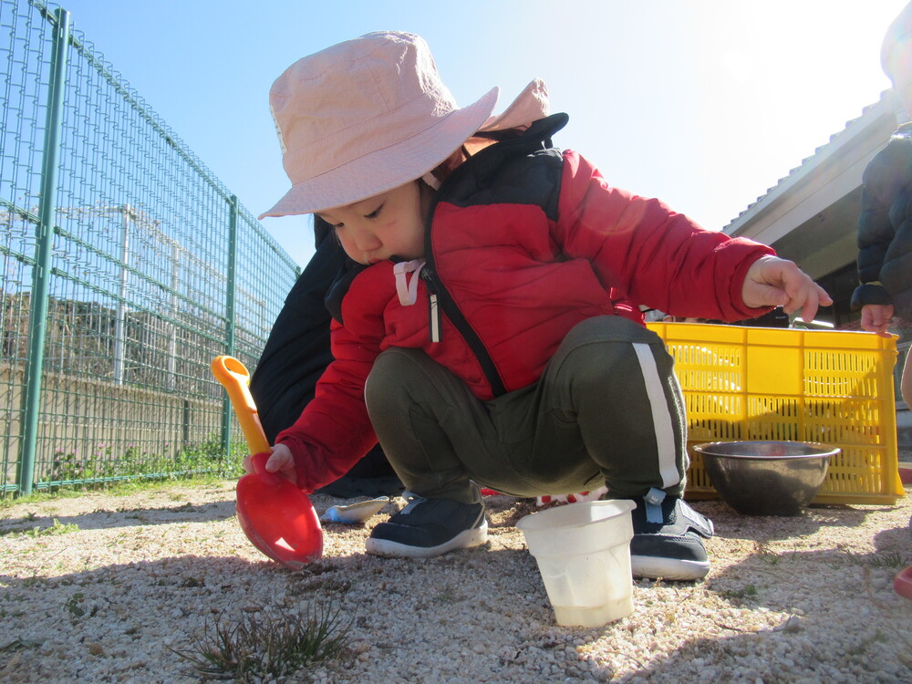 男の子がスコップで砂をすくっている