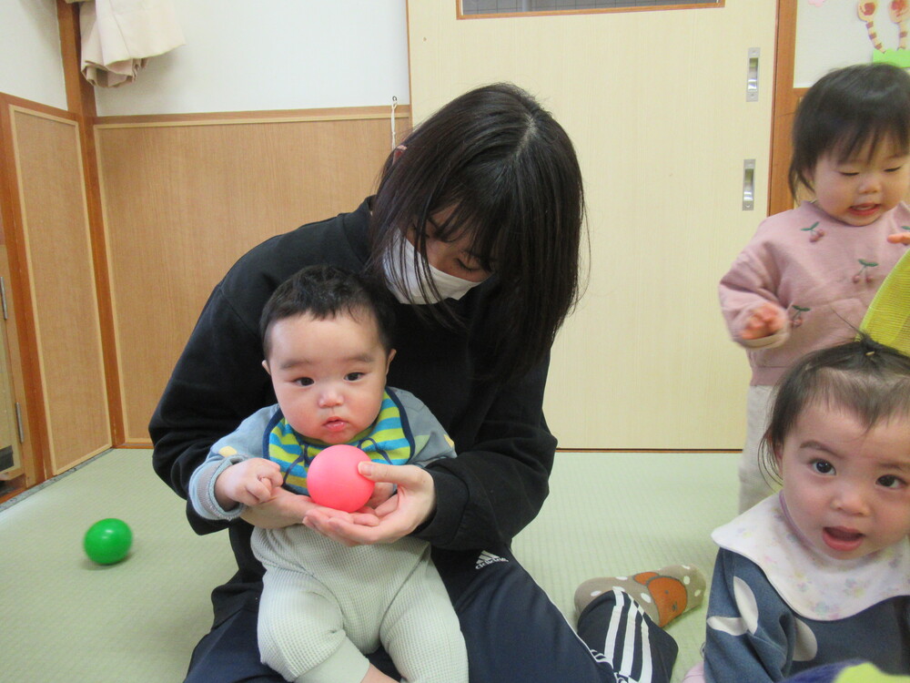 保育者が男の子にボールを渡している