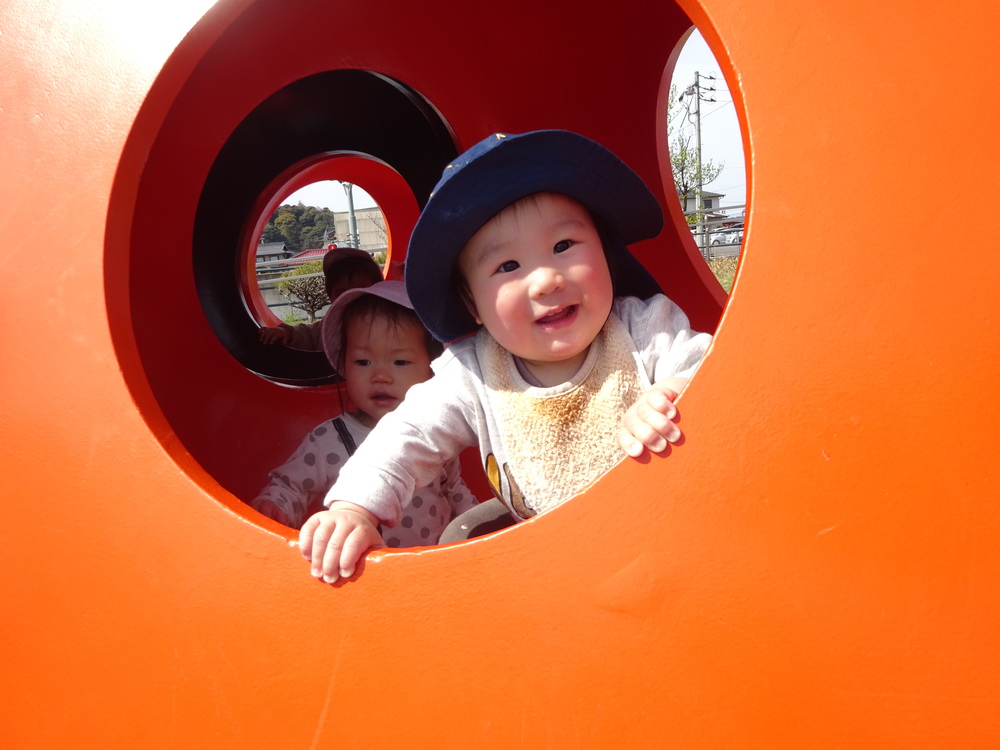 オレンジのオブジェから顔を出している男の子