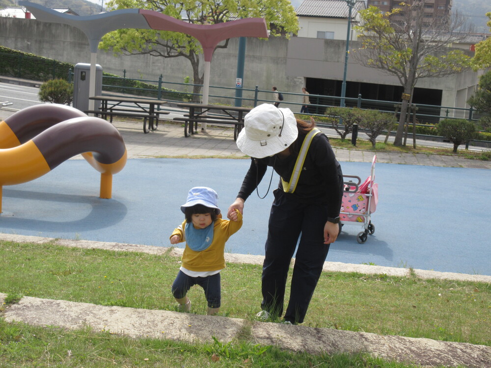 保育者と手をつないで歩いている