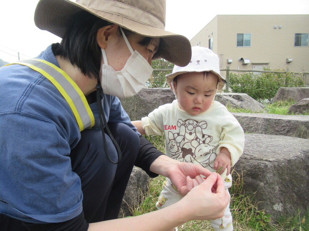 保育者が女の子に葉っぱを渡している