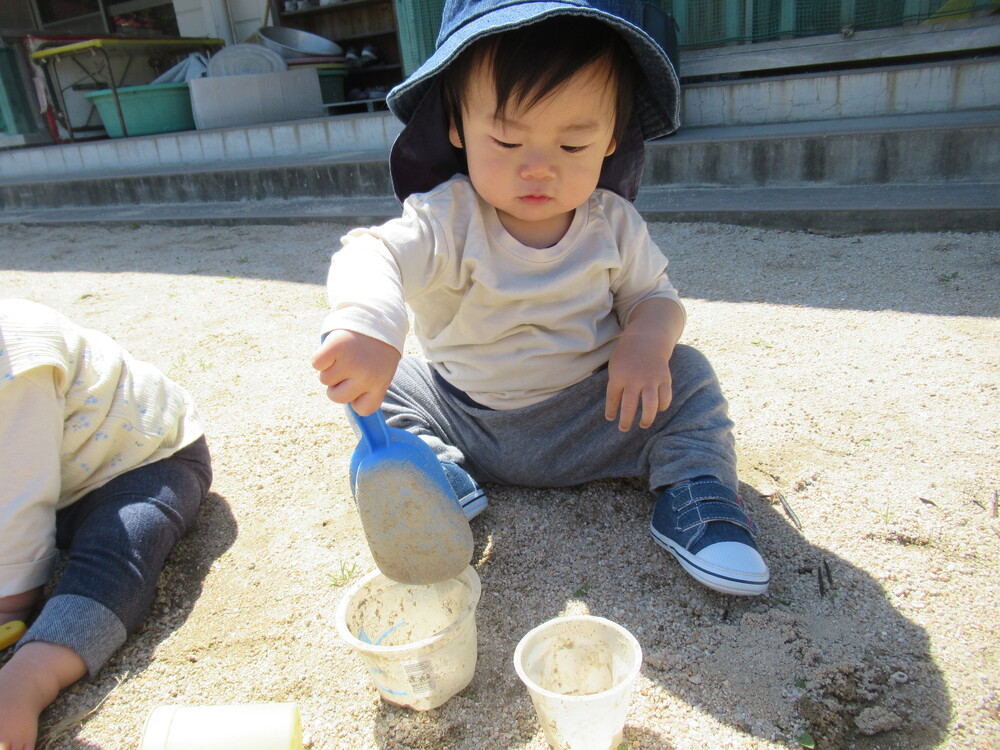 男の子がカップに砂を入れいている