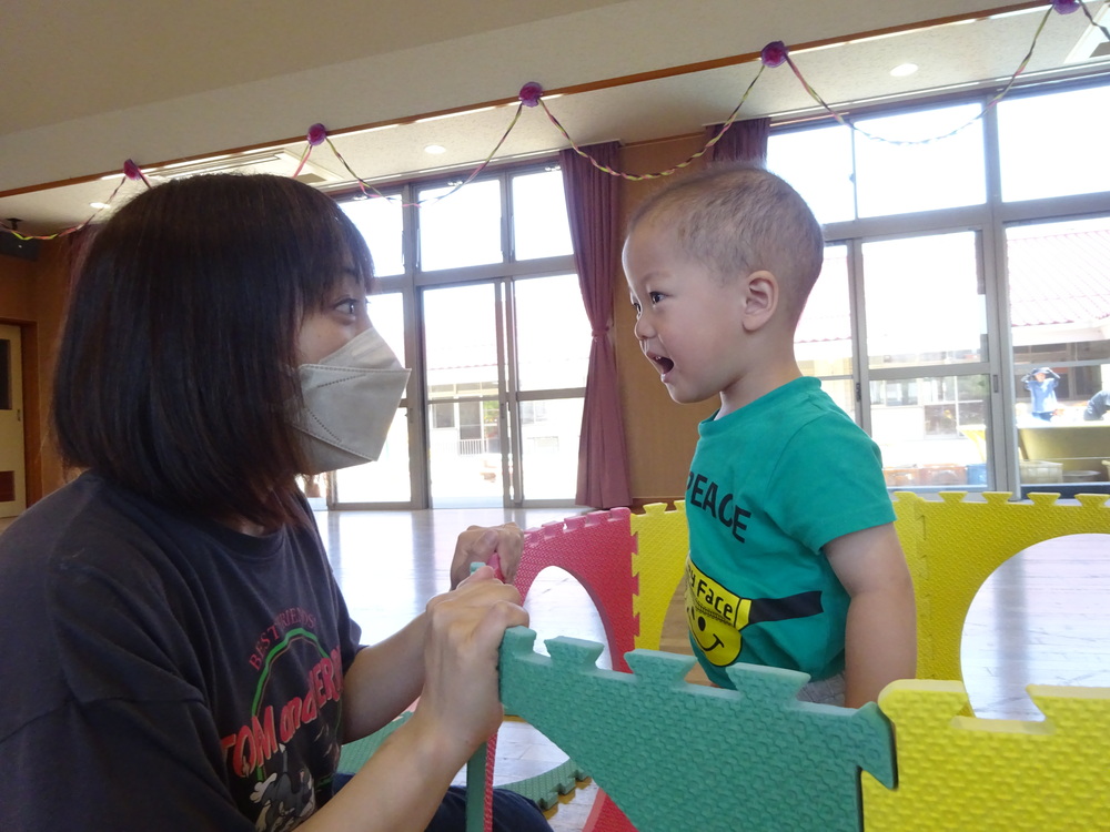 保育者と「ばぁ」をする男の子