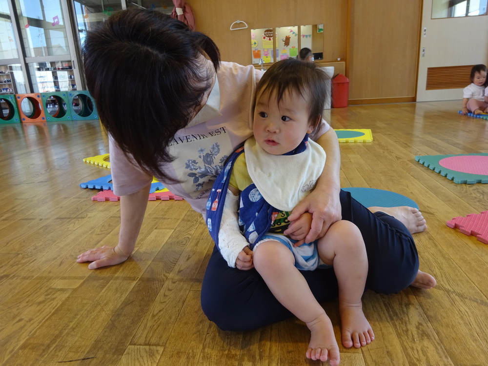 保育者の膝の上に座る男の子