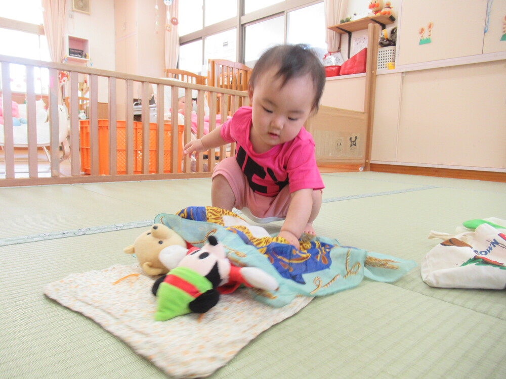 布団にぬいぐるみを寝かせてトントンする子ども