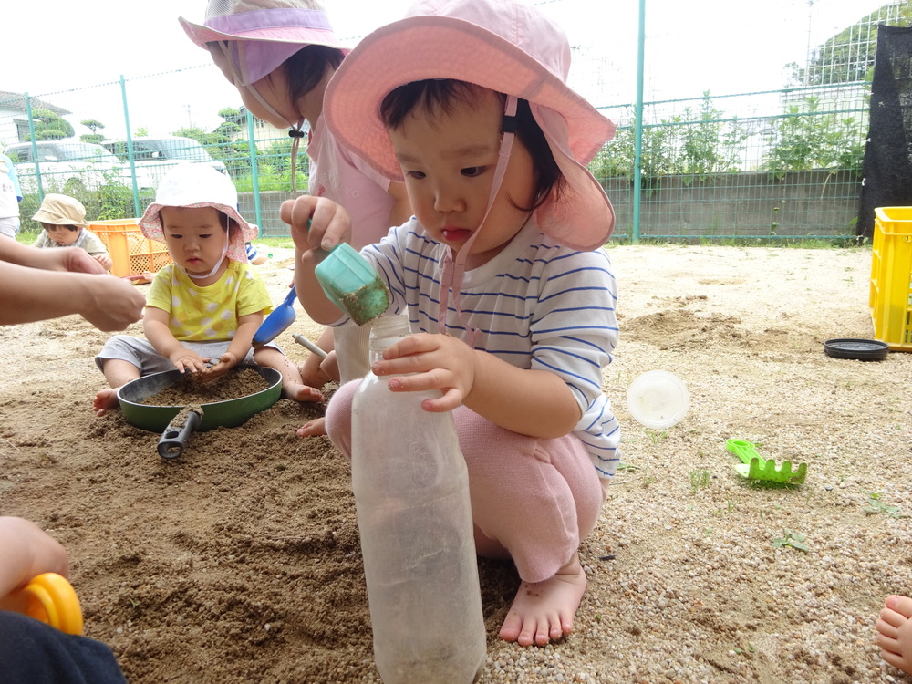 ペットボトルに砂を入れている女の子