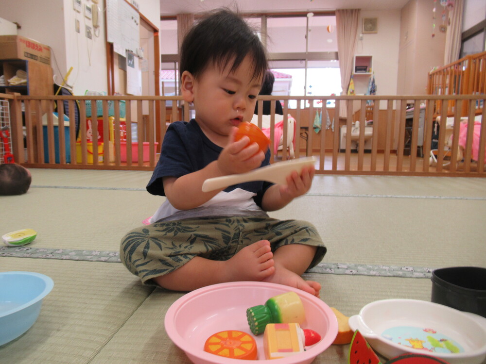 男の子がしゃもじにおもちゃを乗せようとしている