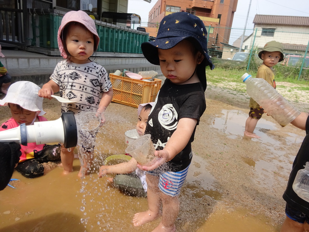 カップに水を入れてもらう男の子