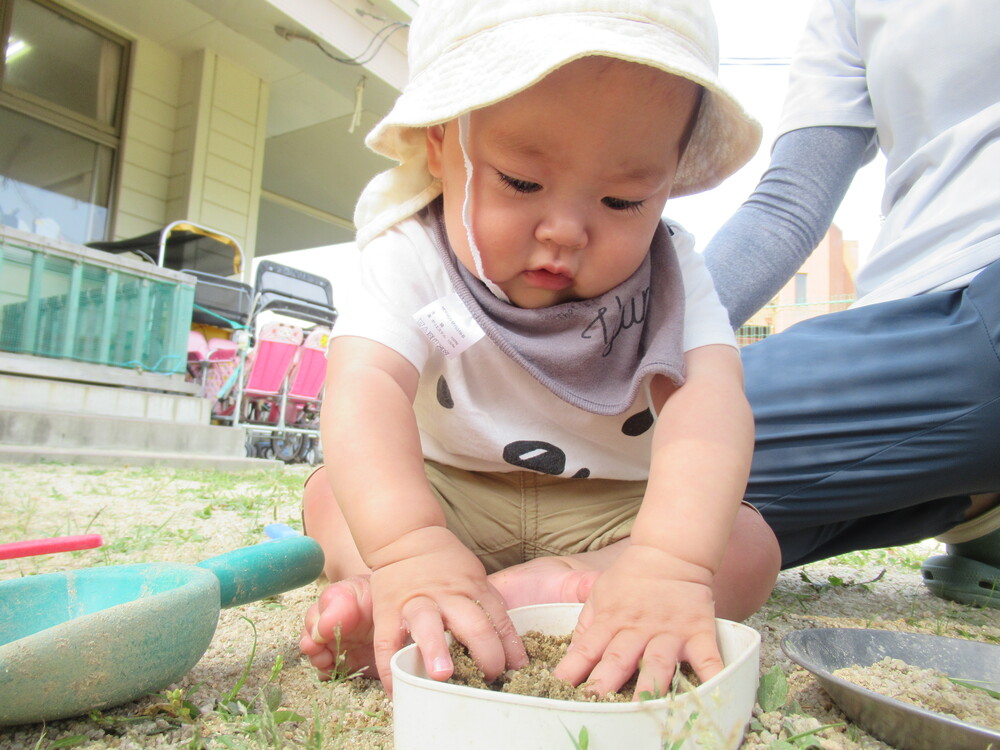 男の子が砂を手で触っている