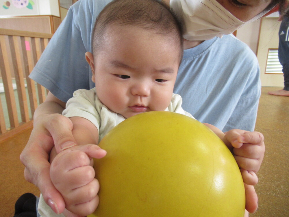 男の子が保育者と一緒にボールを触っている