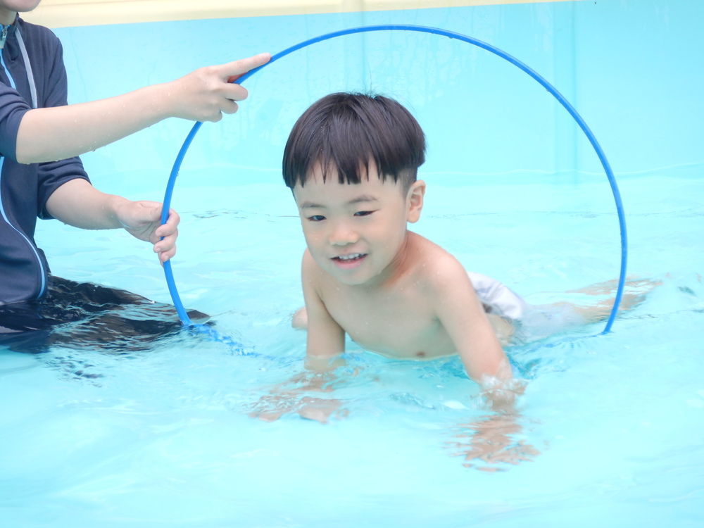 フラフープの中をくぐる男の子