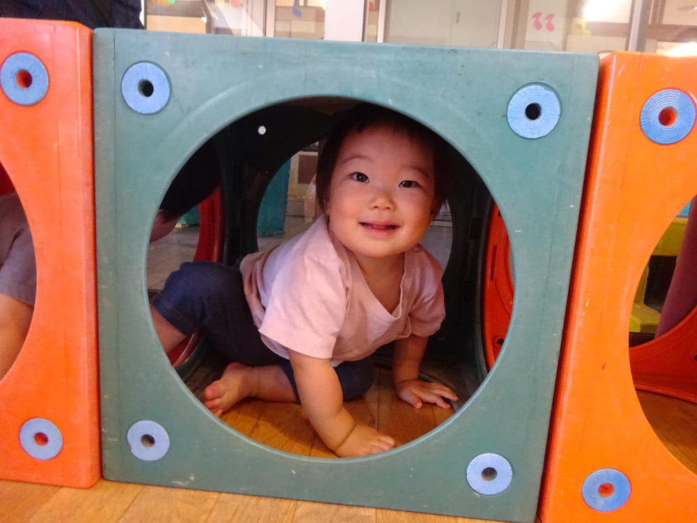 カラーボックスのトンネルで遊ぶ子ども