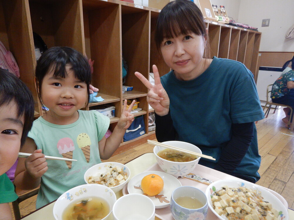 一日保育士で来られたお母さんと一緒に給食を食べている