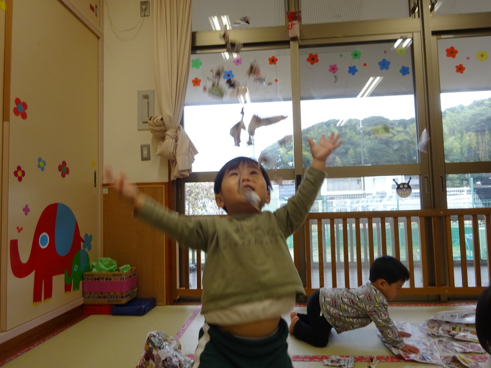 広告紙のシャワーを楽しんでいる子ども (1)