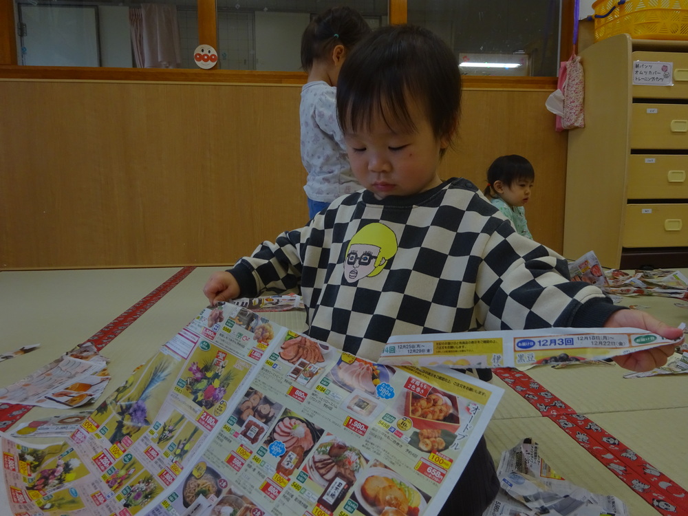 広告紙をちぎっている子ども
