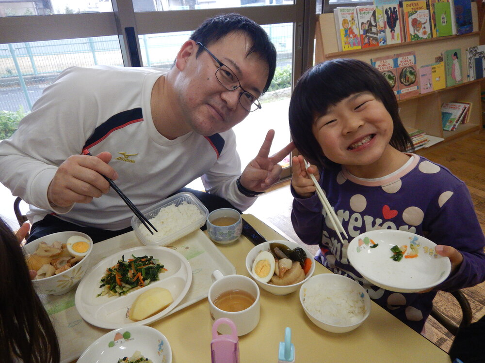 一日保育士のお父さんと一緒に給食を食べている