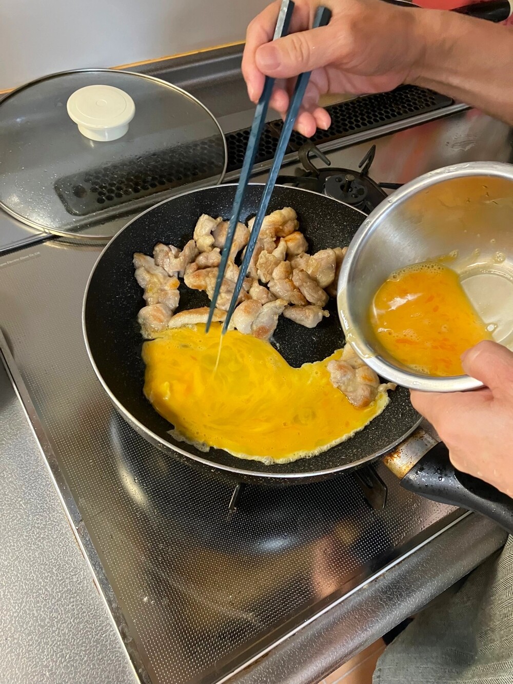 フライパンで肉と卵を焼く