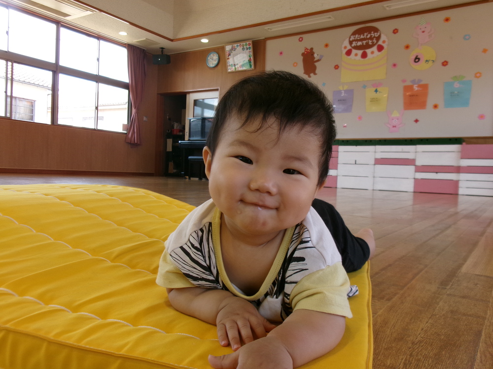 マットでずりばいをする子ども