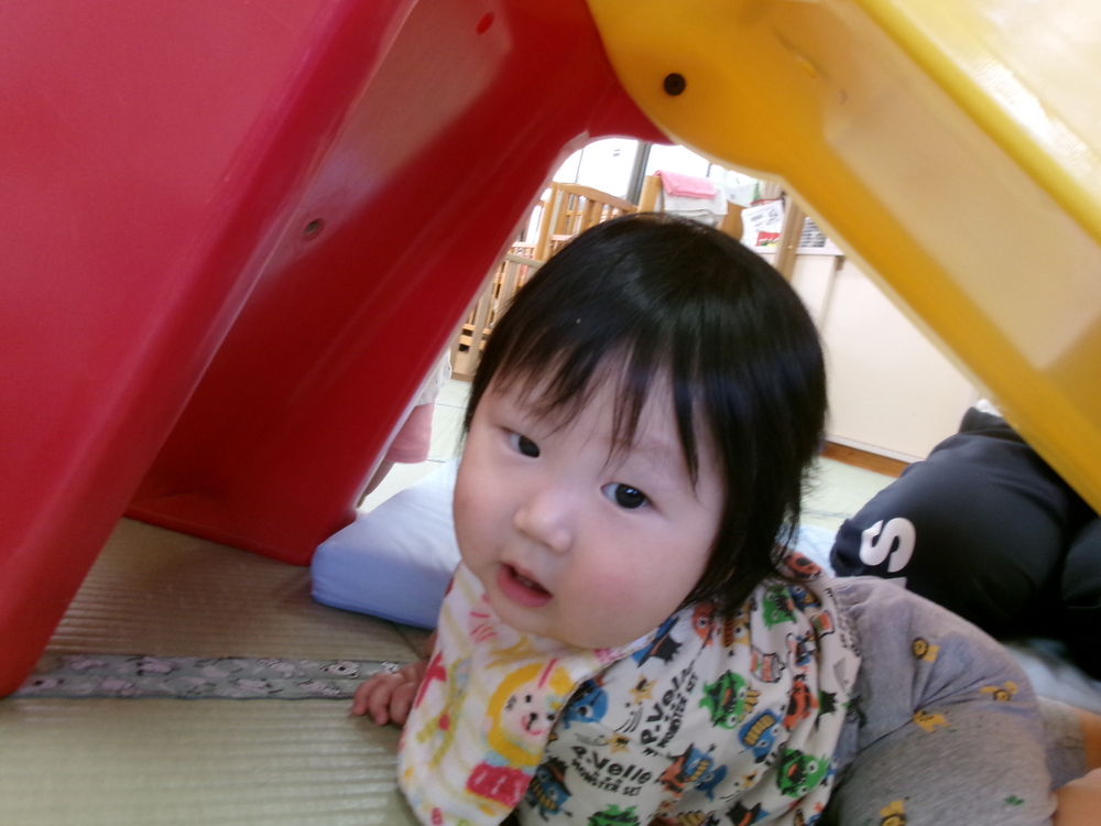 滑り台の下から覗いている子ども
