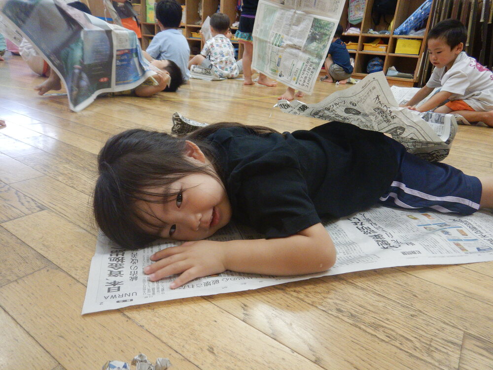 新聞紙の布団で寝る女の子