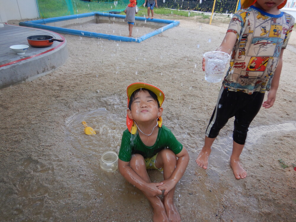 ホースのシャワーの下にいる子ども
