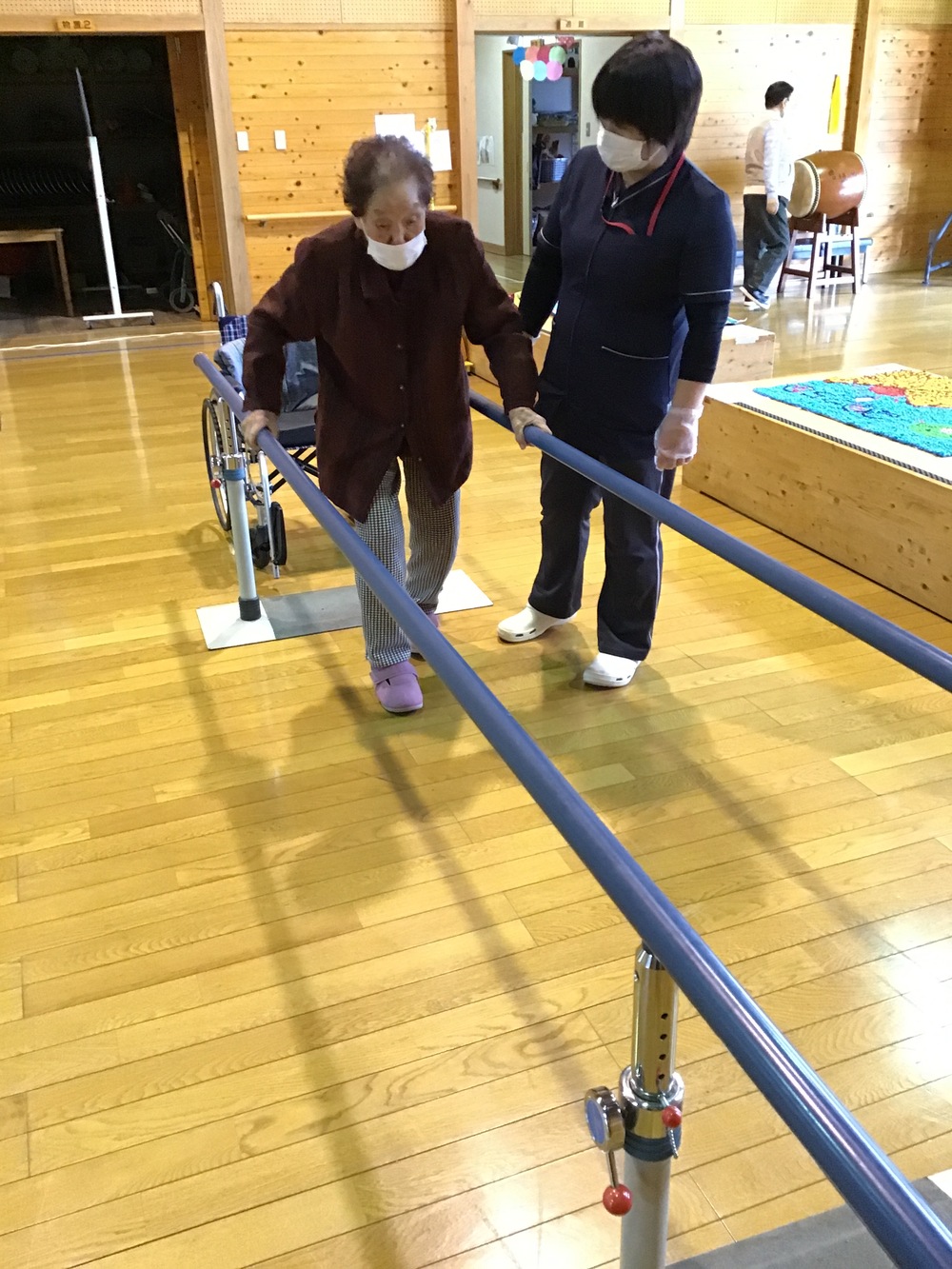 平行棒歩行中の利用者さんと職員