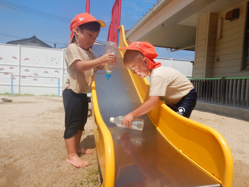遊具に水をかけてあげる子どもたち