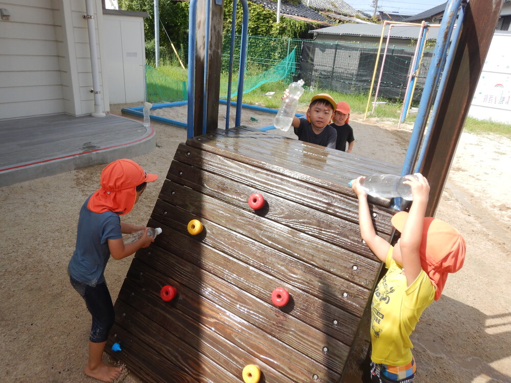 遊具に水をかけて遊ぶ子どもたち