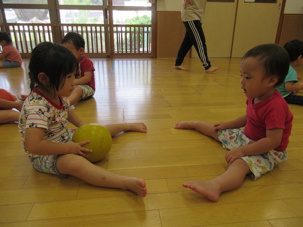 向かい合ってボールを転がす、男の子と女の子