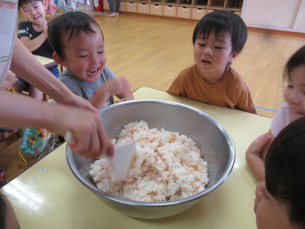 鮭フレークを混ぜている様子を見ている子どもたち