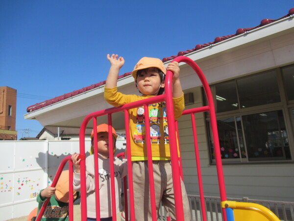 すべり台の上から手を振っている男の子