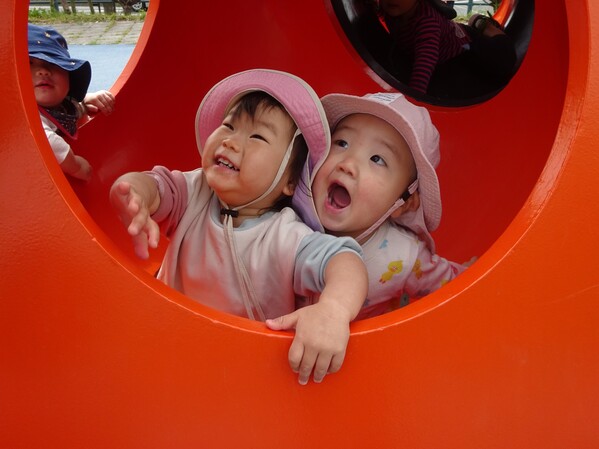 オレンジのオブジェの中から顔を出している子どもたち